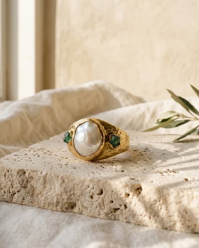 Δαχτυλίδι από σφυρήλατο χρυσό 18K με baroque μαργαριτάρι και φυσικά σμαράγδια, πάνω σε τραβερτίνη στο φως του απογεύματος